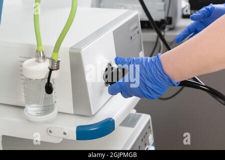 Vorbereitung von Geräten für die medizinische Untersuchung der Videogroskopie. Die Ärzte Hände in blauen Handschuhen verbinden das Endoskop und andere Geräte Stockfoto