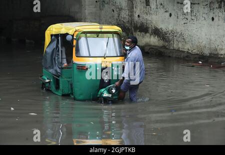 Neu-Delhi, Indien. September 2021. Ein Mann zieht seine Auto-Rikscha durch eine wasserdurchsetzte Zakhira-Unterführung nach starken Regenfällen in Neu-Delhi. Die Verkehrspolizei von Delhi schloss mehrere Unterführungen und Straßen, um den Verkehr aufgrund von starken Regenfällen und Wassereinschlägen in vielen Gebieten zu vermeiden, darunter auch dem internationalen Flughafen Indira Gandhi. Das Indian Meteorological Department (IMD) kündigte Gewitter mit sehr starken Regenfällen in der Hauptstadt an. Kredit: SOPA Images Limited/Alamy Live Nachrichten Stockfoto