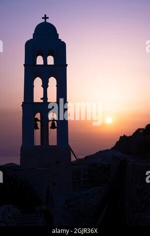 Der Glockenturm der Kirche von Panagia in Chora, Griechenland bei Sonnenuntergang mit den felsigen Klippen in der Ferne Stockfoto