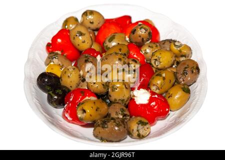 Eingelegte Oliven mit gefüllten Paprika auf einem weißen Teller, isoliert auf weißem Hintergrund Stockfoto