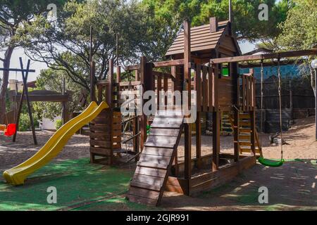 Ein leerer Kinderspielplatz mit Rutschen, Schaukeln und verschiedenen Wegen in einem Pinienwald an der toskanischen Küste, Castagneto Carducci, Livorno, Italien Stockfoto