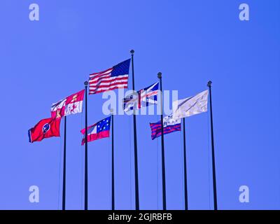 Flaggen am blauen Himmel - aufgenommen auf Mud Island in Memphis Tennessee, einige großartige Nationalflaggen auf sehr hohen Fahnenmasten, die im Wind flattern. Stockfoto