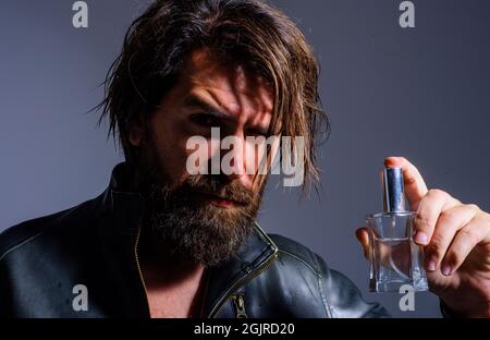 Bärtiger Mann mit Parfüm. Männlicher Duft und Parfümerie. Hübscher Kerl mit kölner Flasche. Herrenkosmetik. Stockfoto