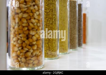 Verschiedene Hülsenfrüchte und Getreide in Glasflaschen Stockfoto