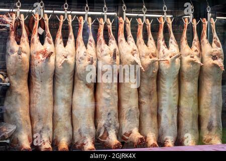 Lammkarkassenfleisch wurde im Schlachthof an Haken gehängt, Metzgerei befindet sich im Kühlschrank. Rohes, ungekochtetes Lammfleisch Stockfoto
