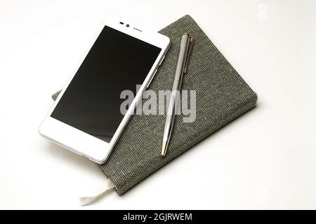 Notebook mit Stift und Smartphone auf weißem Hintergrund isoliert Stockfoto