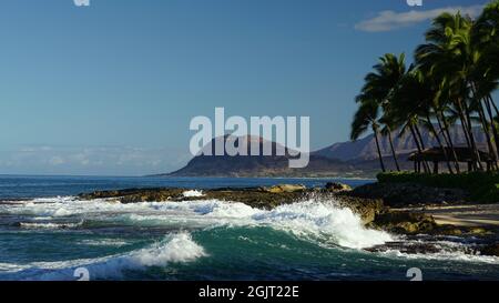 Wellen des Pazifischen Ozeans Rollen in eine Lagune im Ko Olina Resort am westlichen Ufer von Oahu mit den Waianae Bergen in der Ferne. Stockfoto