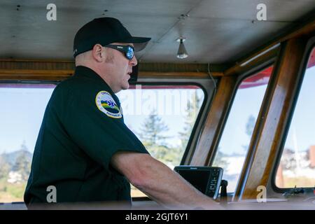 Portland, USA. September 2021. Mark Lamb, ein Feuerwehrmann aus Portland, ist außerdem Notarzt und zertifizierter Hafenpilot; Hafenpiloten sind für die Steuerung und Navigation des Schiffes verantwortlich. Der David Campbell, ein 93 Jahre altes Löschboot, macht seinen endgültigen Einsatz am 9-11-2021 in Portland, Oregon, als Teil des Portland Fire and Rescue-Denkmals für die Feuerwehrleute, die vor zwanzig Jahren bei der Zerstörung des World Trade Center verloren gegangen sind. (Foto von John Rudoff/Sipa USA) Quelle: SIPA USA/Alamy Live News Stockfoto