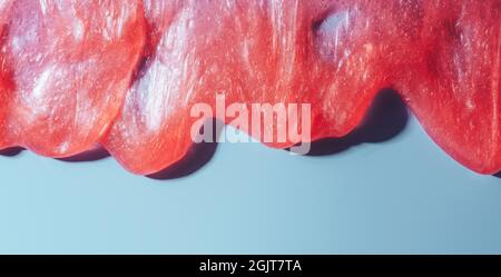 Roter flüssiger Schleim fließt über blauen Hintergrund Stockfoto