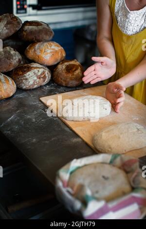 Das Bäckermädchen legt Brotscheiben auf eine Schaufel Stockfoto