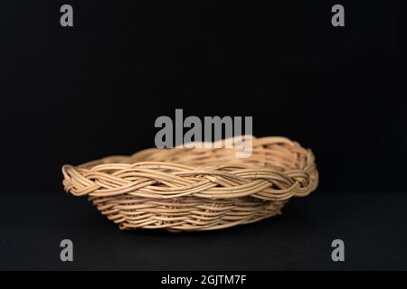 Ein schöner Rattankorb auf schwarzem Hintergrund. Stockfoto