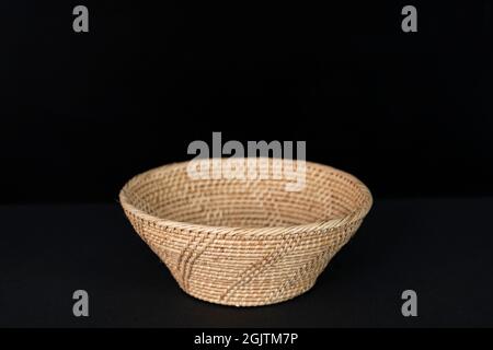 Eine schöne Rattanschale auf schwarzem Hintergrund. Stockfoto