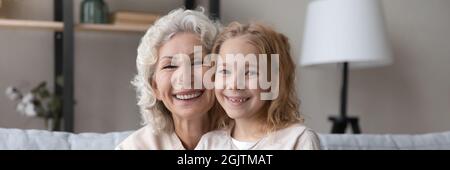 Ältere ältere ältere Frau posiert mit fröhlichen liebenswert Kind Mädchen. Stockfoto