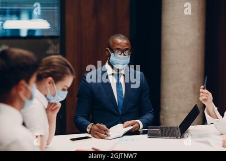 Kollegen unterschiedlichste Team trägt Gesichtsmaske Office Meeting. Geschäftsleute und Frauen Gruppenkonferenz Diskussion Stockfoto