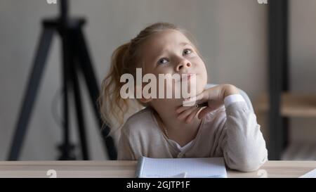 Nachdenkliches kleines Mädchen in Anbetracht schwierige Schulaufgabe. Stockfoto