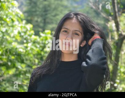 Nahaufnahme eines jungen Mädchens, das im Freien posiert, die Hand durch die Haare bewegt und die Kamera anschaut Stockfoto