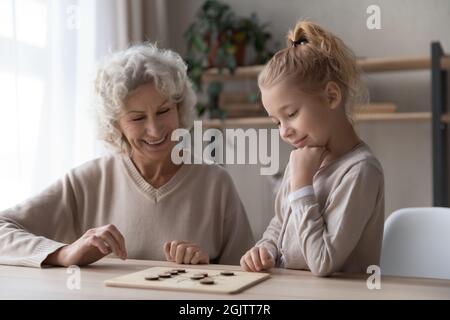 Alte Großmutter spielt Entwürfe mit entzückenden kleinen Mädchen. Stockfoto