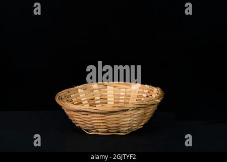 Eine schöne Rattanschale auf schwarzem Hintergrund. Stockfoto