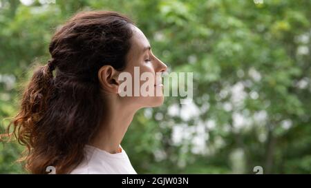 Seitenansicht ruhige junge Frau, die draußen steht und frische Luft atmet Stockfoto