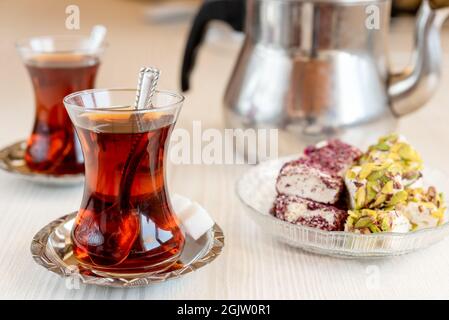 Duftender türkischer Tee in einem speziellen Glas, Teekannen und orientalischen Süßigkeiten Stockfoto