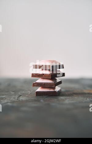 Selektive Konzentration auf vier Schokoladenscheiben auf dunklem Hintergrund. Stockfoto