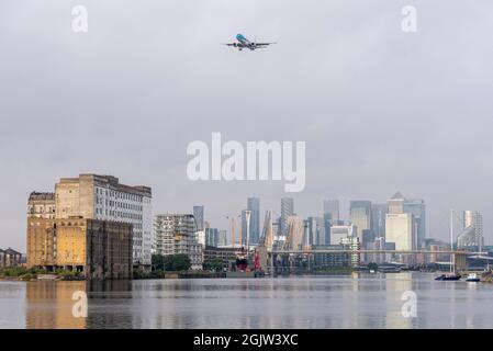 Das Flugzeug landet am London City Airport über dem Finanzviertel von London. Londons Docklands in Newham, Royal Victoria Dock und alte Mühle Stockfoto