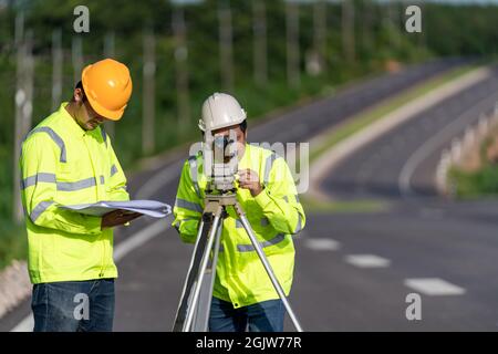 Zwei Vermessungsingenieure mit Ausrüstung auf Straßenbaustellen, Bauingenieure, Vermessungsgeräte. Stockfoto