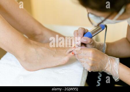 Kosmetikerin, die eine Pediküre malt, um die Nägel ihrer Kundin in einem Beauty-Center zu malen. Stockfoto