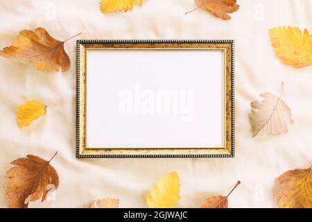 Mockup leerer Rahmen auf einem hellen Hintergrund mit verstreuten Herbstblättern Stockfoto