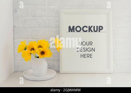 Leerer weißer Rahmen-Mockup mit einem Bouquet aus gelben Sonnenblumenblumen in einer Vintage-Vase auf einem Tablett im Provence-Stil vor einem Hintergrund einer weißen Bric Stockfoto