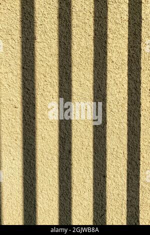 Brauner Hintergrund aus feinem Gips im Freien in der Sonne. Mit Schatten aus Gitter oder Zaun. Nahaufnahme. Stockfoto