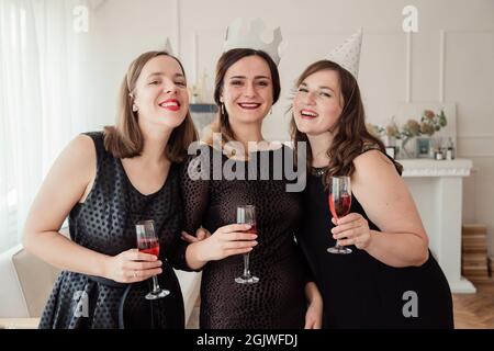 Frauenparty. Freundinnen Mädchen in schwarzen Kleidern mit Weingläsern in den Händen. Geburtstag oder Junggesellinnenabschied Stockfoto