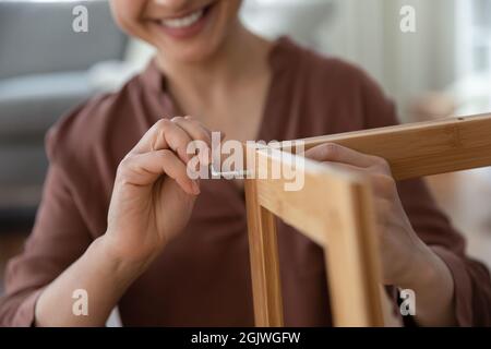 Lächelnde junge Frau, die flache Möbel mit Sechskantschlüssel zusammengebaut hat Stockfoto