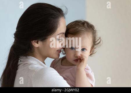 Glückliche neue Mutter hält niedliches Kleinkind Baby in den Armen, lächelnd Stockfoto