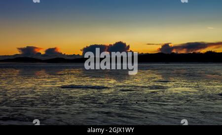 Ein goldener Sonnenuntergang, der sich im Winter über den Wattflächen von Kirkcudbright Bay, Dumfries und Galloway, Schottland, spiegelt Stockfoto