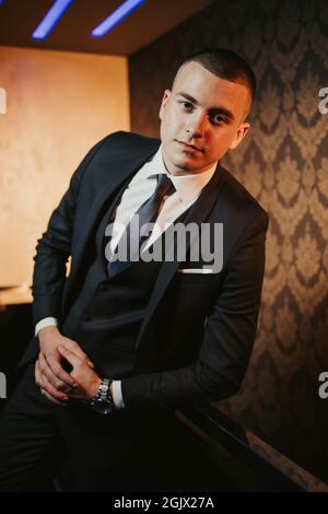 Ein junger, hübscher bosnischer Mann, der in elegantem schwarzen Anzug posiert Stockfoto