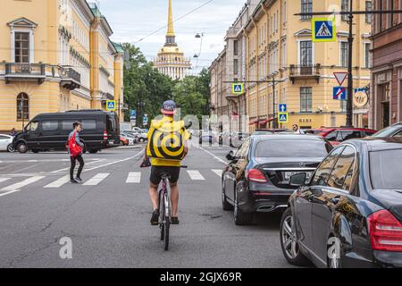 Sankt Petersburg, Russland - 30. Juli 2021: Ein Lebensmittellieferer von Yandex.EDA fährt auf dem Fahrrad die Woznesensky Avenue hinunter. Stockfoto