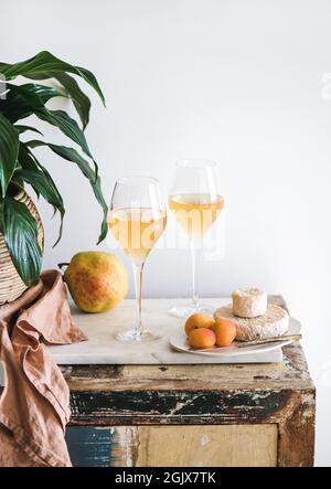 Orangen- oder Bernsteinwein in Gläsern, Obst und Käse Stockfoto
