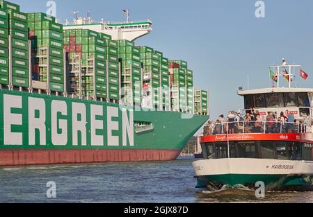 08. September 2021, Hamburg: Passagiere auf einer Hafenfähre auf der Elbe fotografieren das Containerschiff 'Ever Ace' (l). Das 'Ever Ace', eines der größten Containerschiffe der Welt, wurde von Schleppern auf der Elbe in den Hamburger Hafen geführt, um am Containerterminal Burchardkai zu verankern. Das 'Ever Ace' hat offiziell Platz für 23992 Boxen und 200,000 Tonnen Fracht. Foto: Georg Wendt/dpa Stockfoto