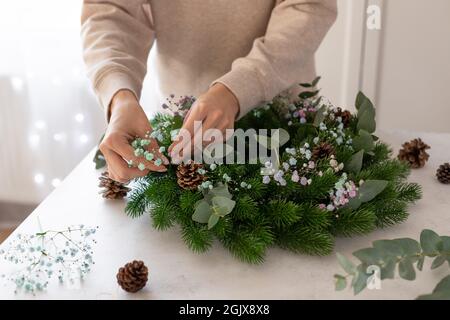 Floristin, die einen Weihnachtskranz mit Gypsophila, Eukalyptus macht Stockfoto