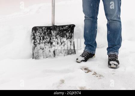 Nahaufnahme der Person mit Schneeschaufel auf der Auffahrt Stockfoto