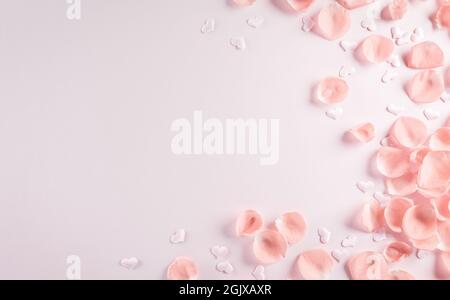 Valentinstag- und Liebeskonzept aus rosa Rosenblättern auf pastellfarbenem Hintergrund. Draufsicht mit Kopierplatz, flach liegend. Stockfoto