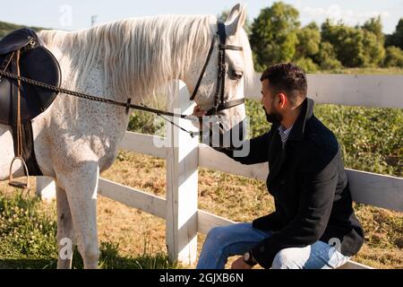 Der Mann ruht mit einem Pferd auf einer Ranch Stockfoto