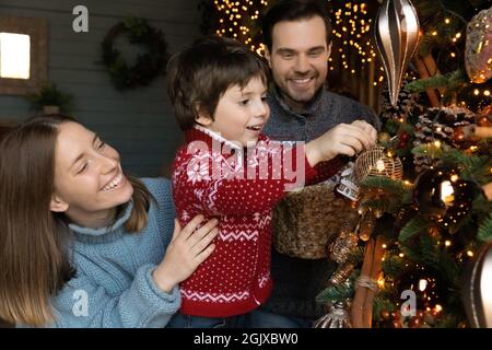 Glückliche liebevolle Familie dekorieren Baum für Frohe Weihnachten. Stockfoto