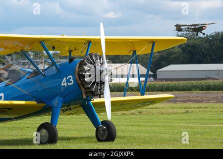 Boeing Stearman-Doppeldecker-Trainingsflugzeug aus dem 2. Weltkrieg mit einem alten Piper Cub-Warbird, der im Hintergrund fliegt Stockfoto