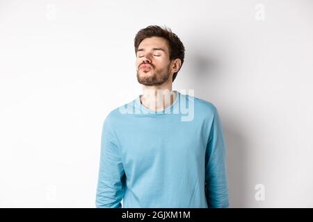 Bild von niedlichen und albern Mann wartet auf Kuss, Pucker Lippen mit geschlossenen Augen, stehen über weißem Hintergrund Stockfoto