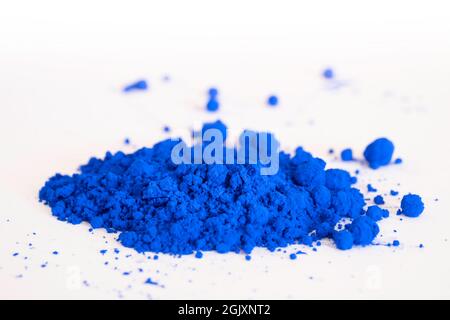 Nahaufnahme eines Teils des blauen Pigments, das in der Seitenansicht auf Weiß isoliert ist. Das Pigment wird mit Leinöl gemischt, um Ölfarbe zu erhalten. Selektiver Fokus Stockfoto