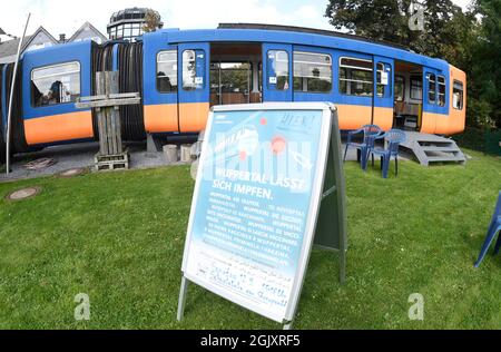 Wuppertal, Deutschland. September 2021. Ein Plakat "Wuppertal lässt sich impfen", mit dem die Stadt zur Impfung gegen das Coronavirus aufruft, steht auf einem Spielplatz vor einem stillgefachten Schwebebahnwagen. Geimpfte können sich dort während der Sonderaktion ohne Registrierung impfen lassen. Quelle: Roberto Pfeil/dpa/Alamy Live News Stockfoto