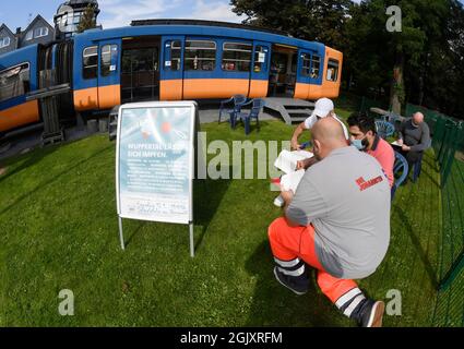 Wuppertal, Deutschland. September 2021. Ein Mitarbeiter hilft zwei Personen, die geimpft werden wollen, die Papiere für die erste Impfung gegen Corona in einem stillgehaltenen Eisenbahnwaggon auf einem Spielplatz auszufüllen. Geimpfte können sich dort während der Sonderaktion ohne Registrierung impfen lassen. Quelle: Roberto Pfeil/dpa/Alamy Live News Stockfoto