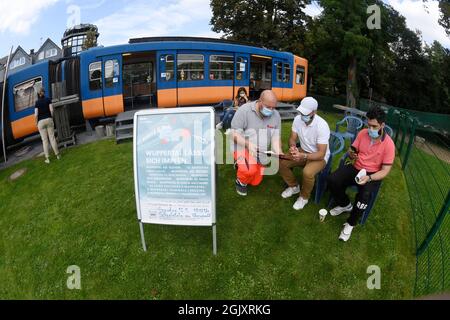 Wuppertal, Deutschland. September 2021. Ein Mitarbeiter hilft zwei Personen, die geimpft werden wollen, die Papiere für die erste Impfung gegen Corona in einem stillgehaltenen Eisenbahnwaggon auf einem Spielplatz auszufüllen. Geimpfte können sich dort während der Sonderaktion ohne Registrierung impfen lassen. Quelle: Roberto Pfeil/dpa/Alamy Live News Stockfoto